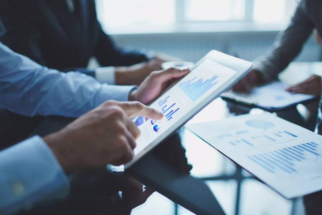 Profissionais analisando dados em tablet e gráficos impressos no contexto da gestão estratégica de pessoas