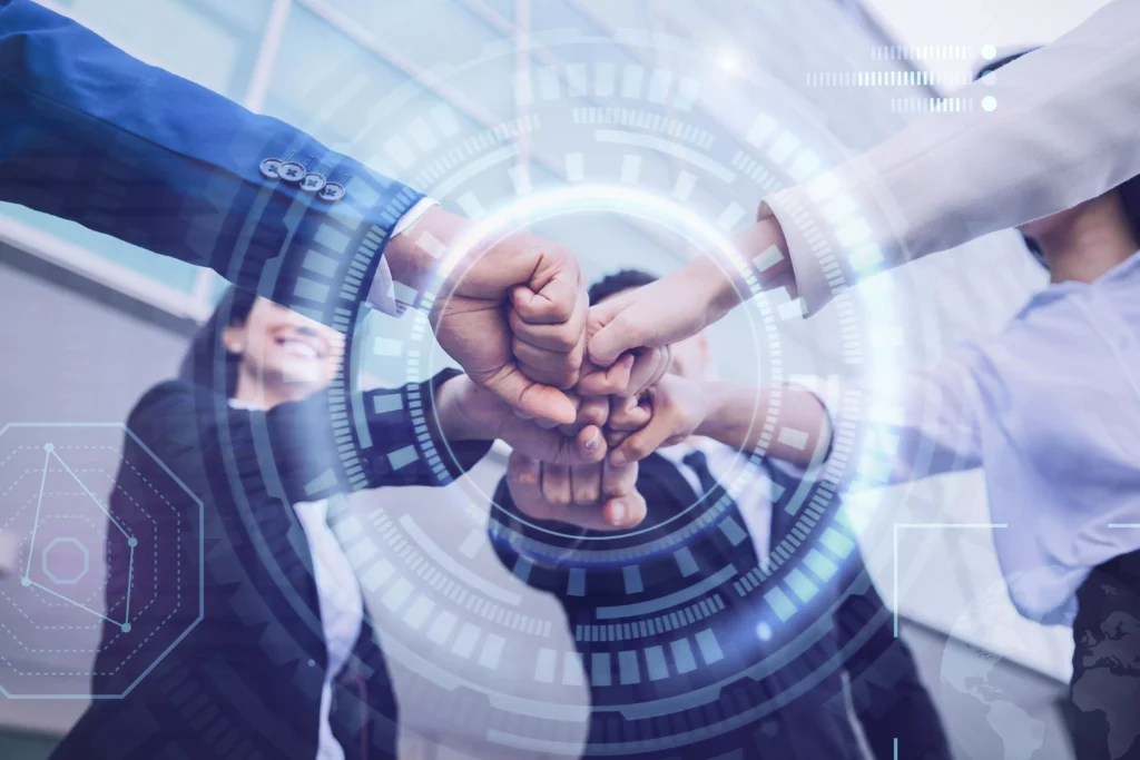 Equipe unindo os punhos em gesto de parceria com elementos gráficos de tecnologia sobrepostos, representando a gestão estratégica de pessoas