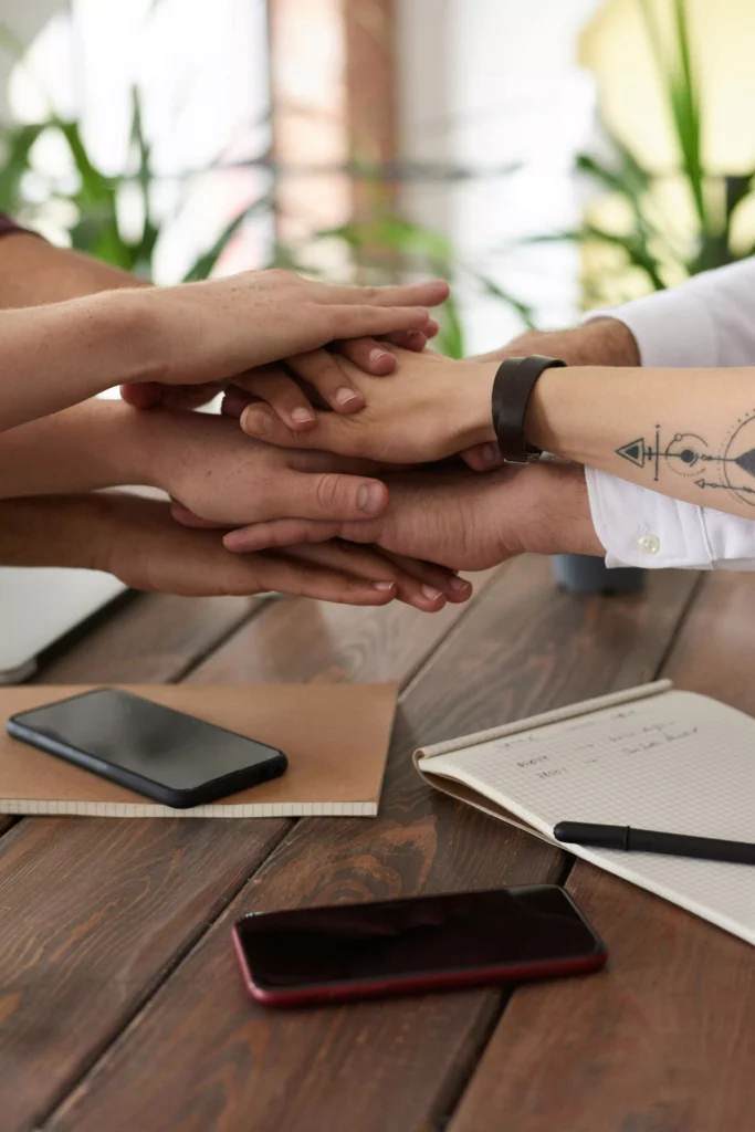 mãos unidas sobre mesa, representando união e motivação coletiva