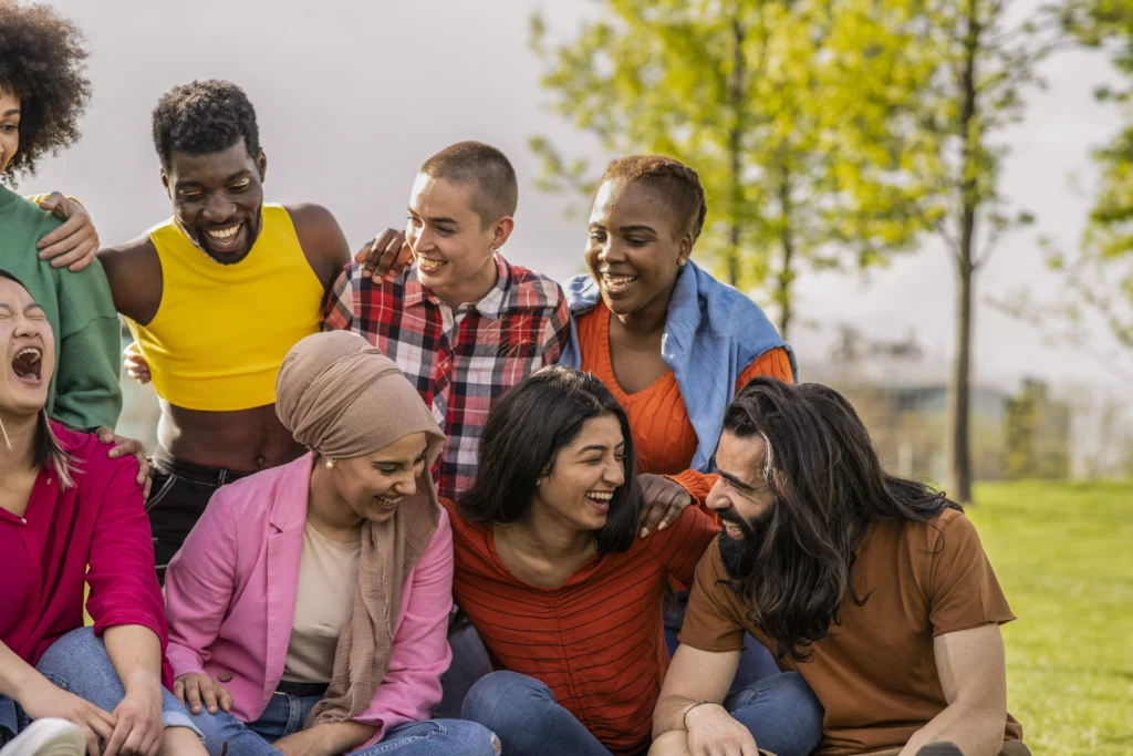Grupo diverso de pessoas rindo e interagindo ao ar livre