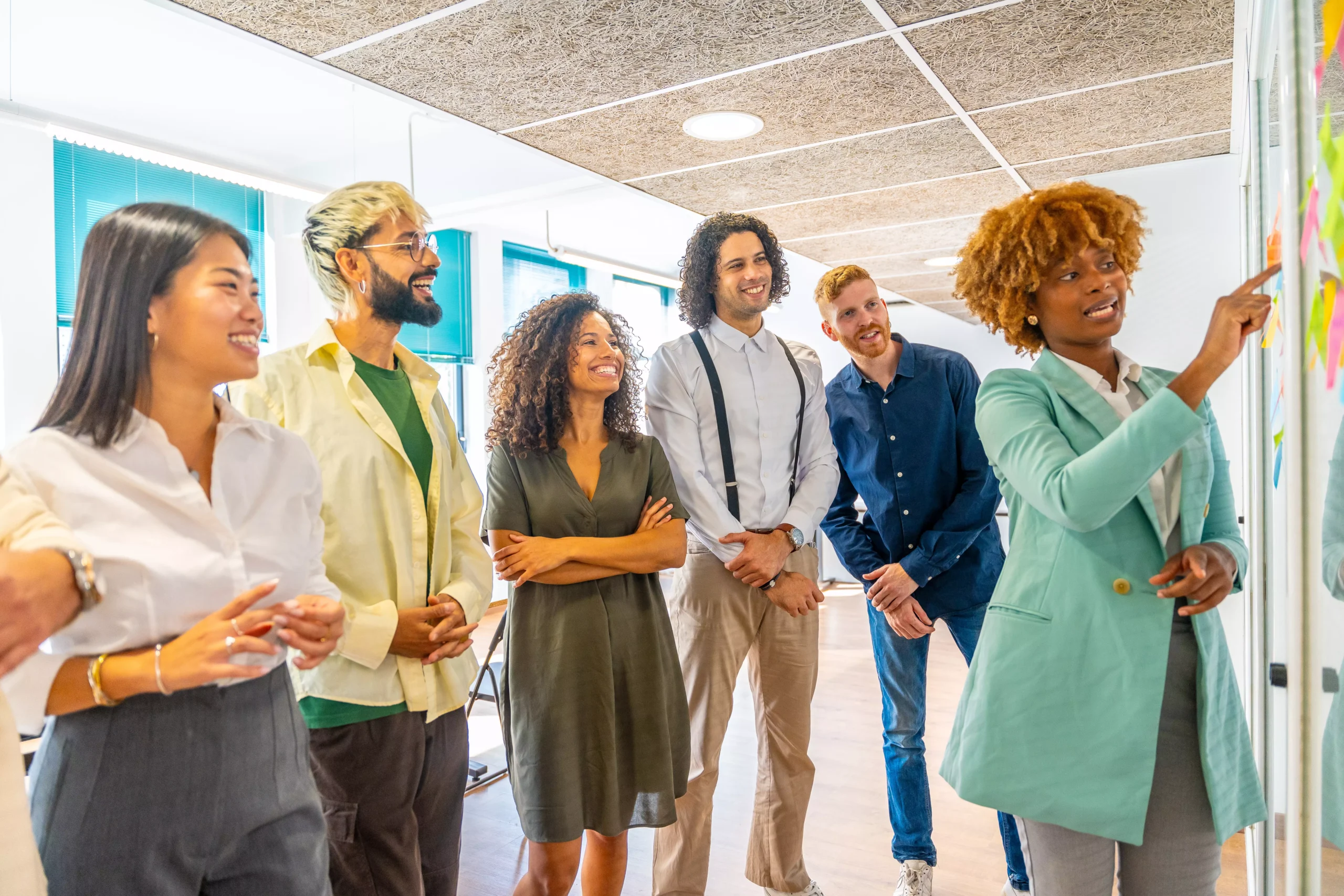 liderança comportamental Equipe diversa reunida ao redor de quadro de ideias, com foco em mulher liderando atividade colaborativa, representando liderança comportamental prática.