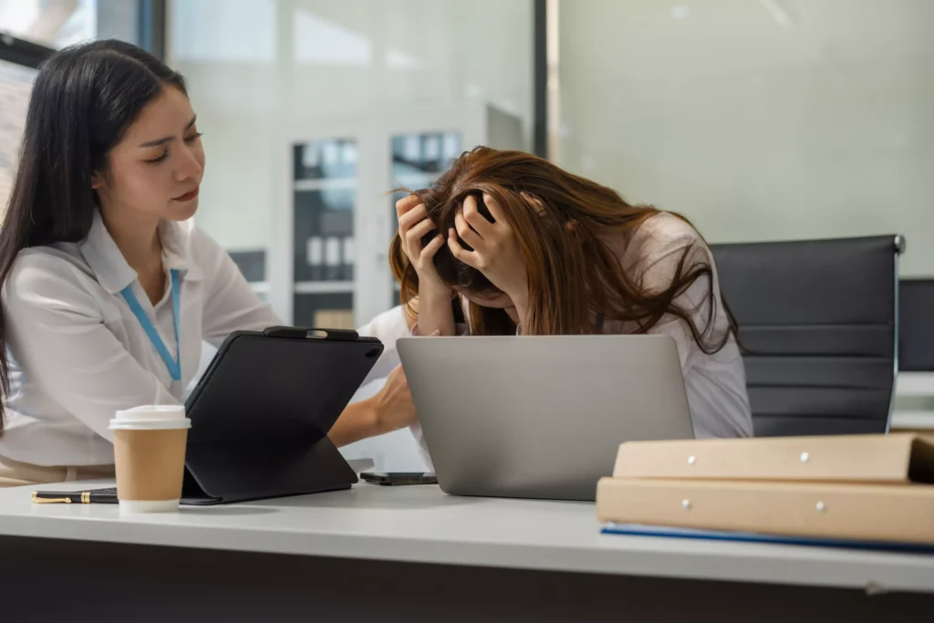 Colega de trabalho oferecendo apoio a funcionária visivelmente abalada emocionalmente