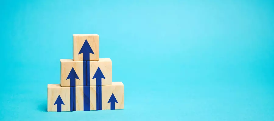 mentalidade financeira Blocos empilhados com setas para cima, representando a ascensão na carreira através da gestão de benefícios.