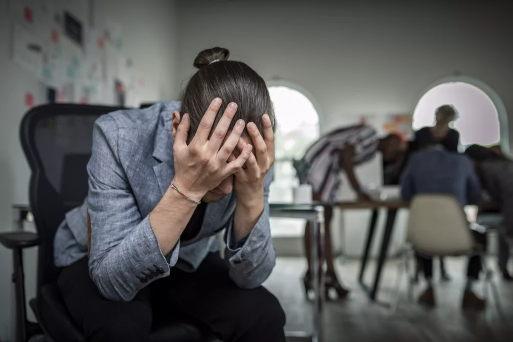 Colaborador com as mãos no rosto expressando estresse no ambiente de trabalho