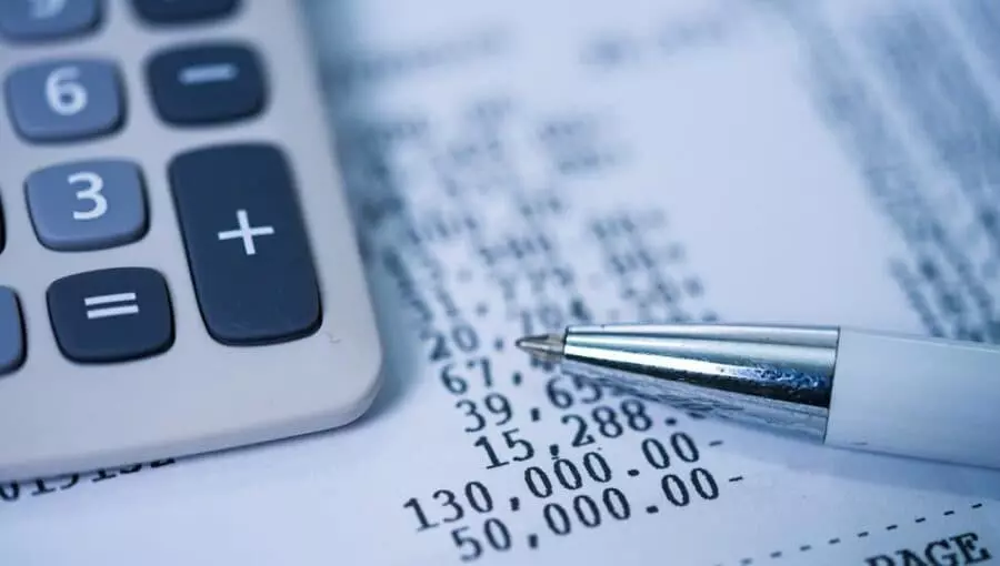 contabilidade nas empresas Calculadora e caneta sobre relatório financeiro com valores destacados, representando a contabilidade empresarial.